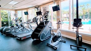 Une salle de sport équipée de tapis de course, de vélos elliptiques et d’un banc de musculation.