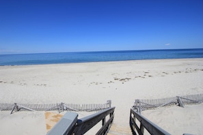 A beach with a wooden walkway leading to the water.