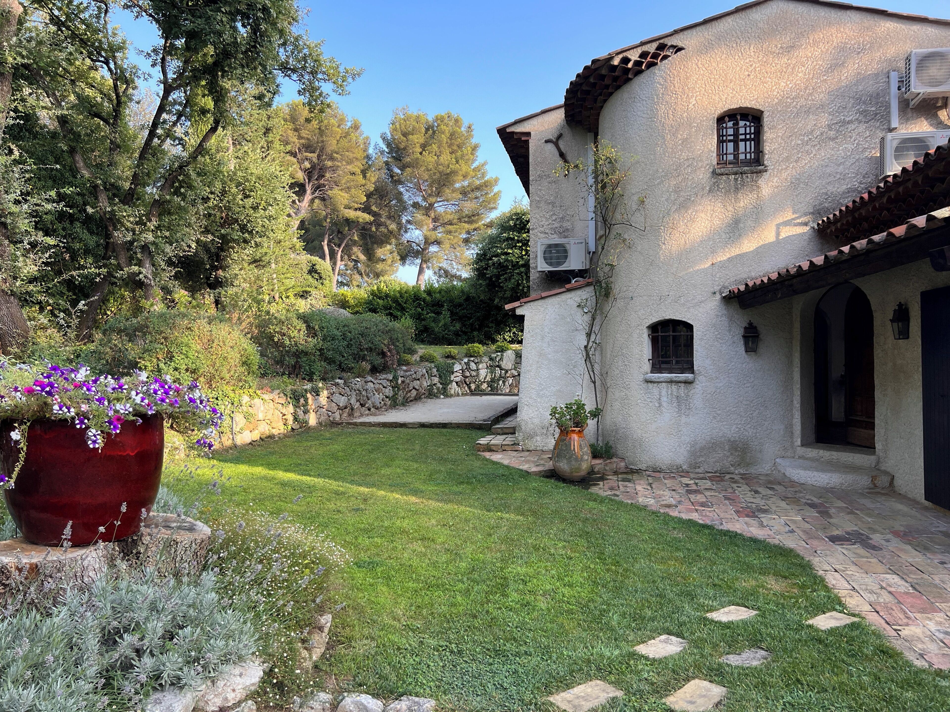 Un bâtiment rustique avec un mur en pierre, un chemin pavé et une pelouse verdoyante.