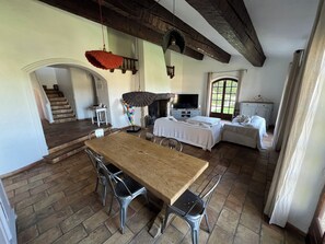 A spacious dining area with a wooden table and metal chairs, a TV, and a fireplace.