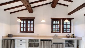 Una cocina con dos ventanas, un lavamanos empotrado y una encimera con un tostador.