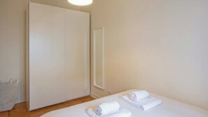 A hotel room with a bed, a wardrobe, a mirror, and a bedside table with towels. - Cosy 1 BDR Apt Belem Sleeps 4 (Lisboa)