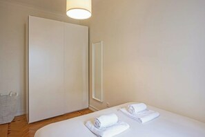 Une chambre d’hôtel comprenant un lit, une armoire, un miroir et une table de chevet avec des serviettes.