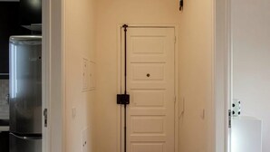 A hallway with a white door, a refrigerator, and a microwave. - Cosy 1 BDR Apt Belem Sleeps 4 (Lisboa)