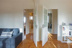 A living room with a sofa, a bookshelf, and a door leading to another room.