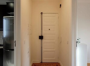 A hallway with a white door, a refrigerator, and a microwave.