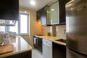 A modern kitchen with a dishwasher, oven, and refrigerator.