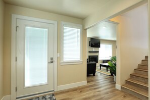 A hallway with a wooden floor, a staircase, and a living area with a fireplace. - Large Townhouse in Downtown Pismo, Sleeps 12! (Pismo Beach)