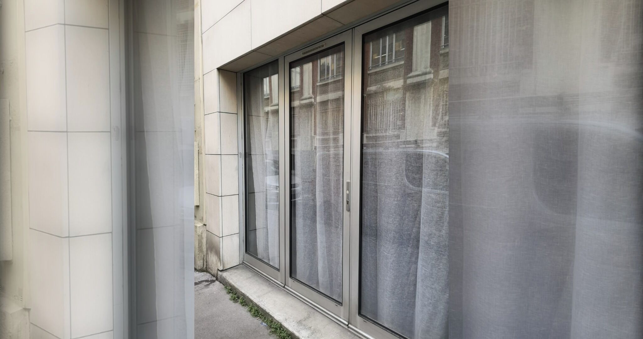 Une façade d’immeuble avec de grandes fenêtres et un étroit passage piétonnier.