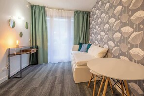 Ein Zimmer mit einem Bett, einem Tisch, einem Schreibtisch und einem Fenster mit Vorhängen.