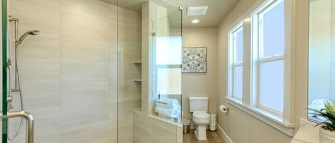 Un baño moderno con ducha de vidrio, inodoro y lavamanos.