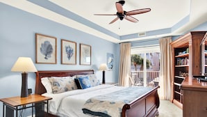 Un dormitorio con una cama grande, dos lámparas de noche, un ventilador de techo y vistas al exterior.