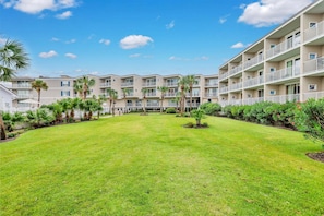A multi-story hotel with a central courtyard, surrounded by lush greenery and palm trees.