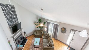Uma sala de estar ampla com lareira, um conjunto de sofás e um ventilador de teto.