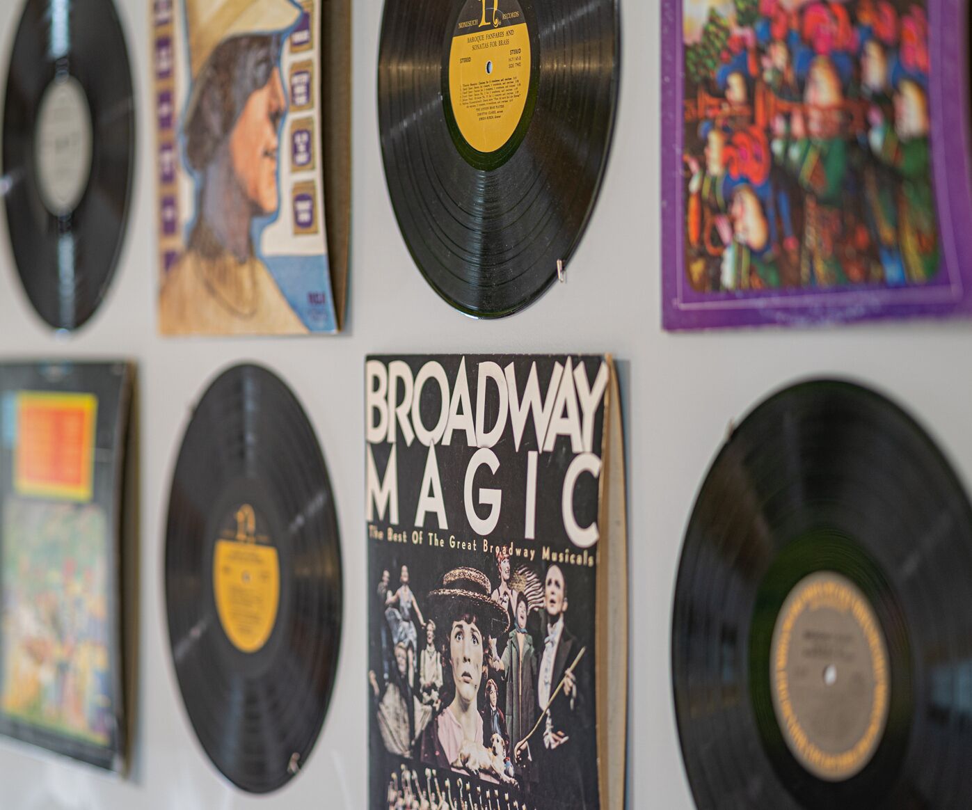 Un mur orné de plusieurs disques vinyle et d’une affiche intitulée « Broadway Magic ».