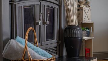A wicker basket with folded towels, a black vase, and a wooden cabinet with a decorative handle.