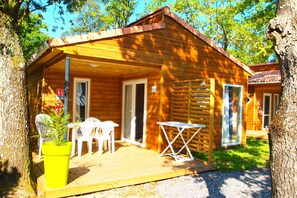 A wooden cabin with a porch, a table, and chairs.