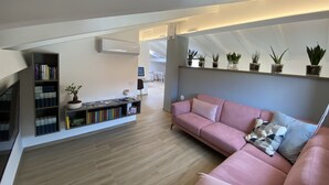 Una sala de estar moderna con un sofá rosa, una estantería y una repisa para plantas montada en la pared.