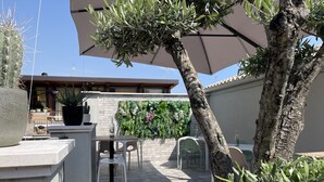 Un patio al aire libre con una mesa, sillas, una planta en maceta y un árbol.