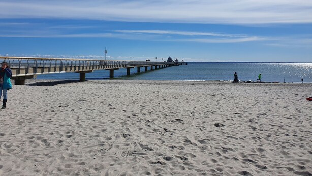 A beach with a pier extending into the water, featuring a bench and a small structure. - Holstenläger - close to the center (Grömitz)