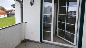 A balcony with a tiled floor, a sliding glass door, and a view of a residential area. - Holstenläger - close to the center (Grömitz)