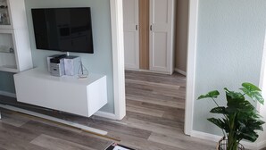 A room with a white entertainment unit, a flat-screen TV, and a plant. - Holstenläger - close to the center (Grömitz)