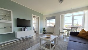 A modern living room with a flat-screen TV, white furniture, and large windows. - Holstenläger - close to the center (Grömitz)