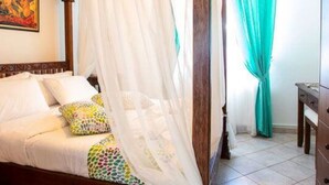 Un lit à baldaquin avec des poteaux aux quatre coins, une tête de lit en bois et une couvre-lit aux couleurs vives.
