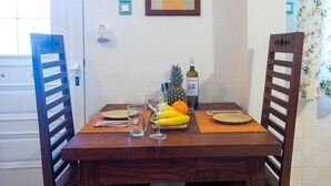 Une table à manger avec des chaises, un ananas, des bananes, une bouteille de vin et des verres.