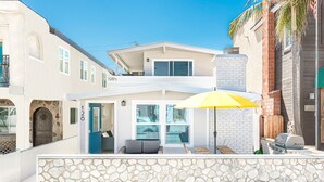 A two-story building with a stone wall in front, a blue door, and a yellow umbrella.