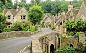A stone bridge over a narrow road in a village with traditional stone houses, surrounded by greenery. - NEW LISTING - Chic Apt in Central Cheltenham Free Permit Parking (Cheltenham)