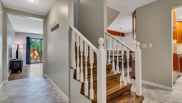 A modern interior with a wooden staircase, grey walls, and a dining area visible in the background. - Walk In, Pointe Royale, Indoor Pool, pickleball (Branson)