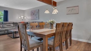 A dining area with a wooden table and chairs, a ceiling light fixture, and a 'gather' sign on the wall. - Walk In, Pointe Royale, Indoor Pool, pickleball (Branson)