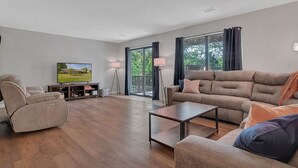 A modern living room with a flat-screen TV, a reclining chair, a sofa, and a coffee table. - Walk In, Pointe Royale, Indoor Pool, pickleball (Branson)
