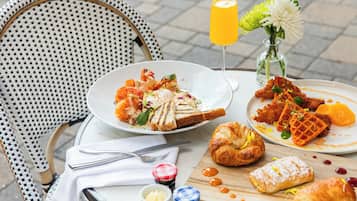 A table set with breakfast items including croissants, waffles, and a glass of orange juice.