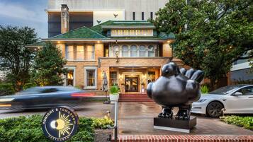 A hotel with a prominent entrance, a large sculpture in front, and a sign indicating it is a restaurant.