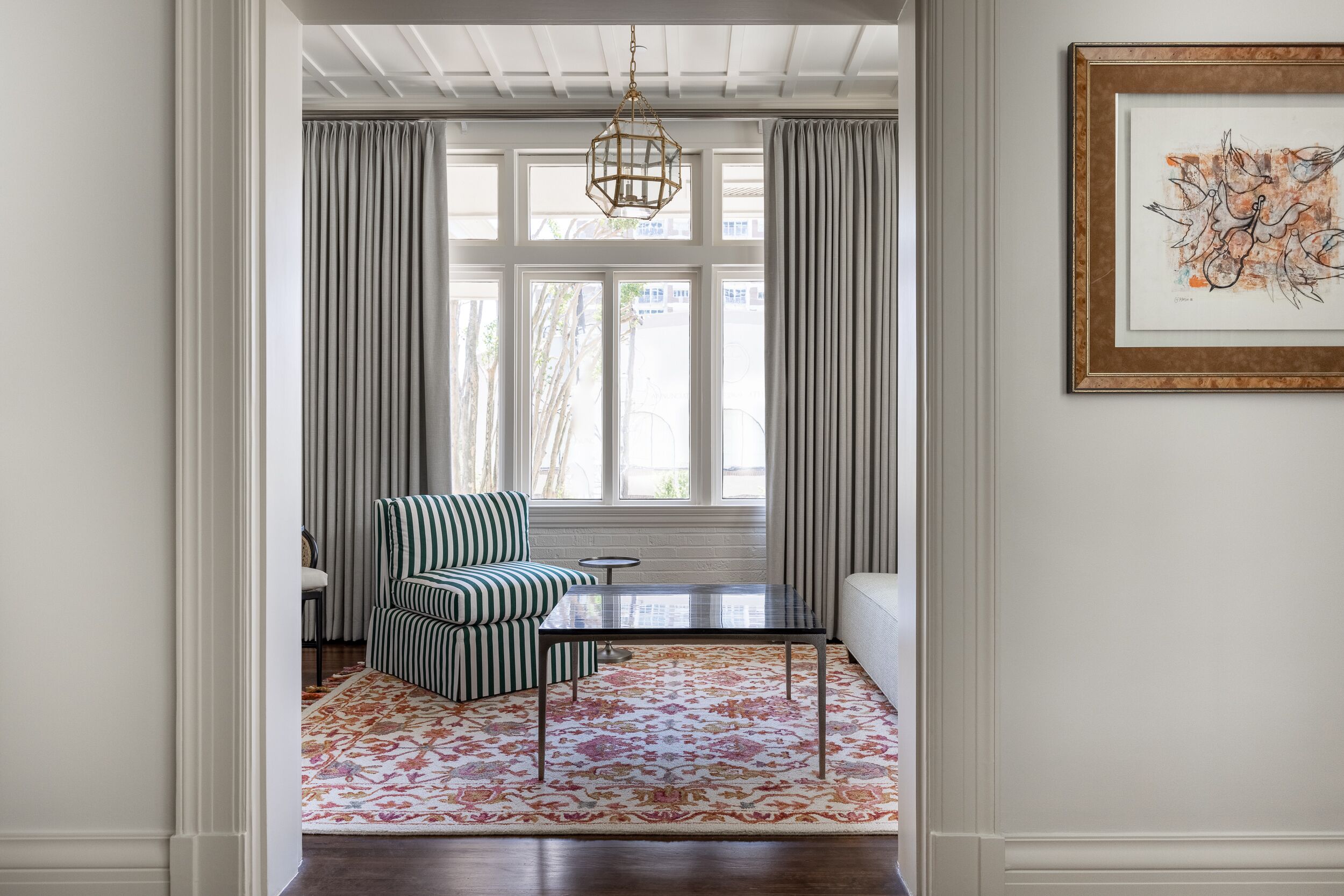 A room with a striped armchair, a small table, and a patterned rug.