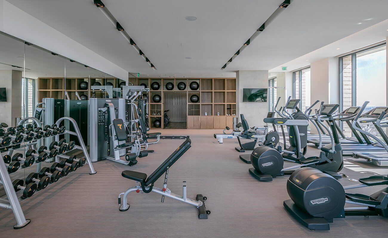 A modern gym with various exercise equipment, including treadmills, dumbbells, and weight machines.