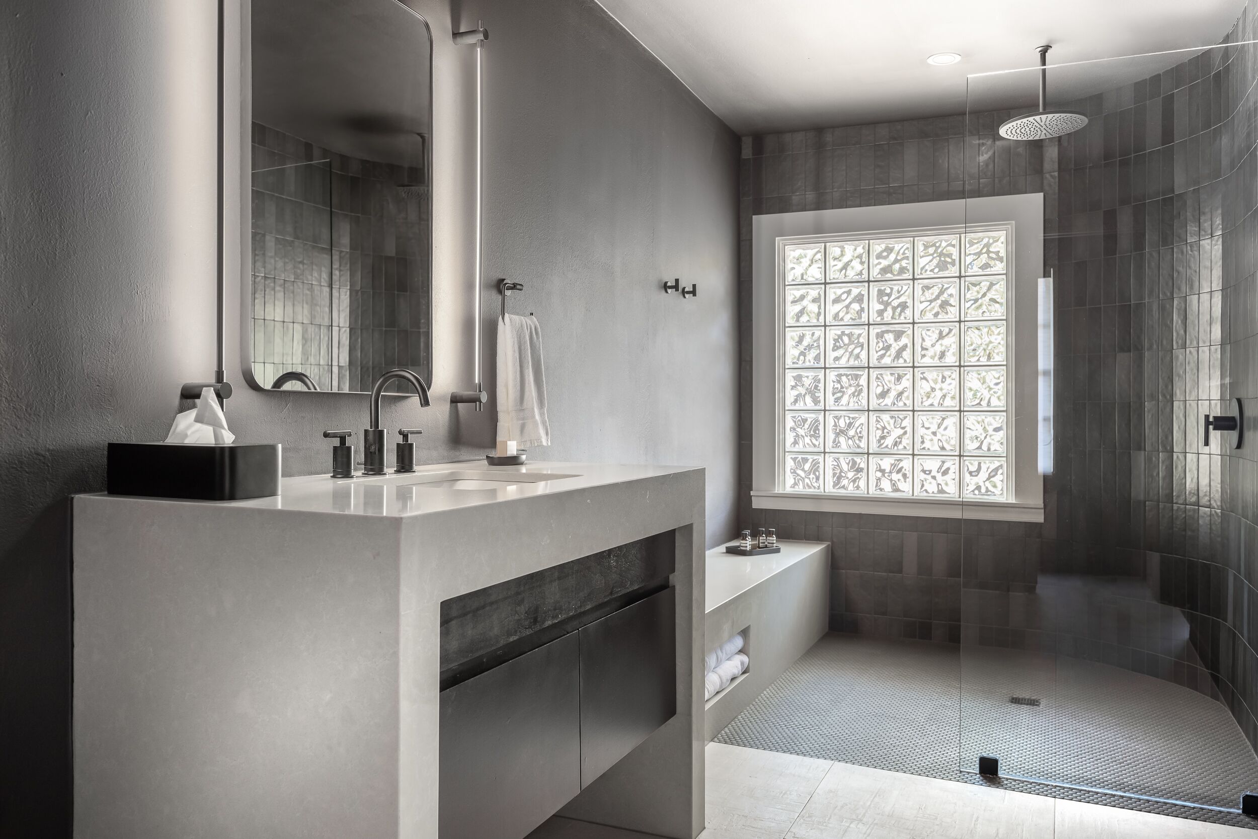 Une salle de bain moderne avec un grand miroir, un lavabo, une douche et une fenêtre décorative.
