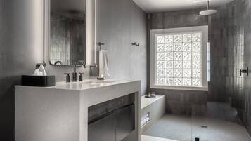 A modern bathroom with a large mirror, a sink, a shower, and a decorative window.