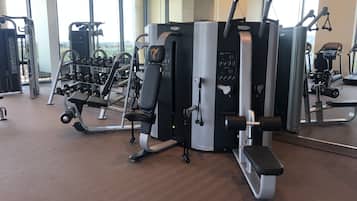 Une salle de sport équipée de divers appareils d’exercice, d’un banc et d’haltères.