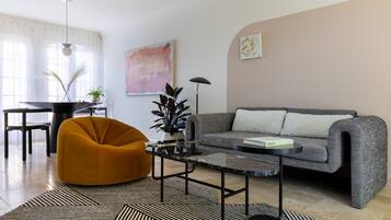 A modern living room with a sofa, a yellow chair, a coffee table, and a dining area with a table and chairs.