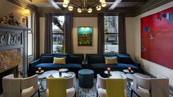 A modern lounge with two sofas, round tables, and a fireplace.