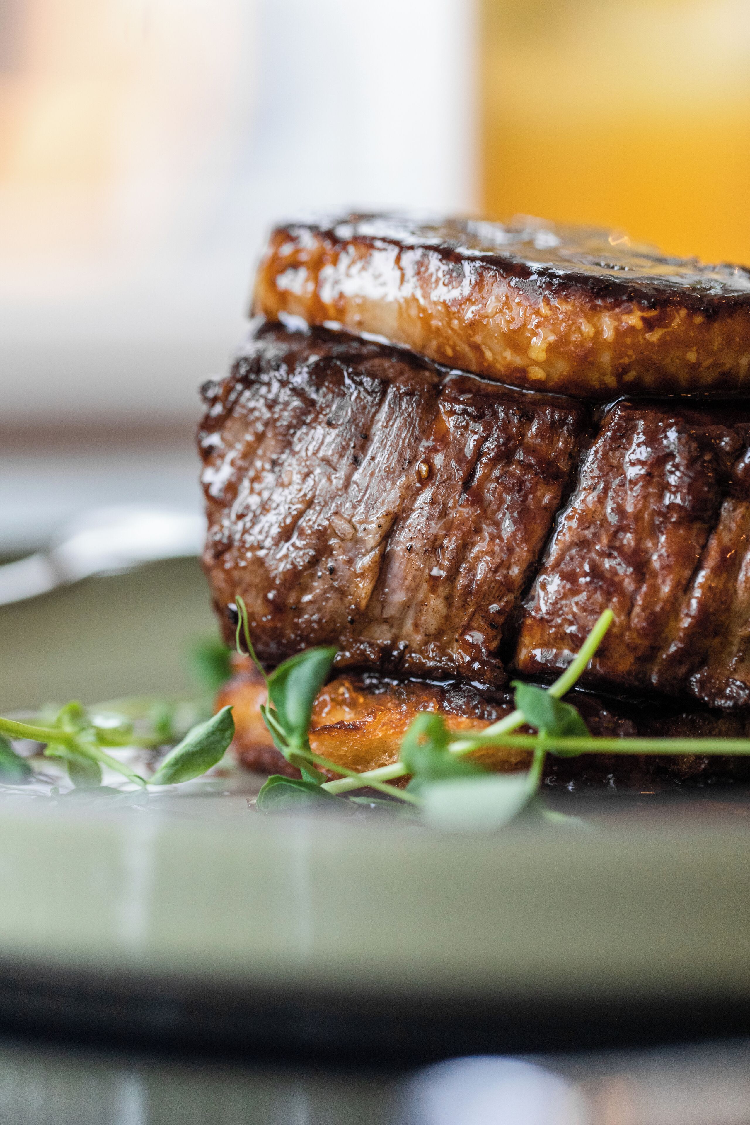 Primer plano de un bistec con una corteza brillante y caramelizada, servido en un plato con guarnición de verduras frescas.