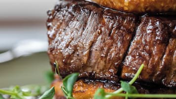 Primer plano de un bistec con una corteza brillante y caramelizada, servido en un plato con guarnición de verduras frescas.