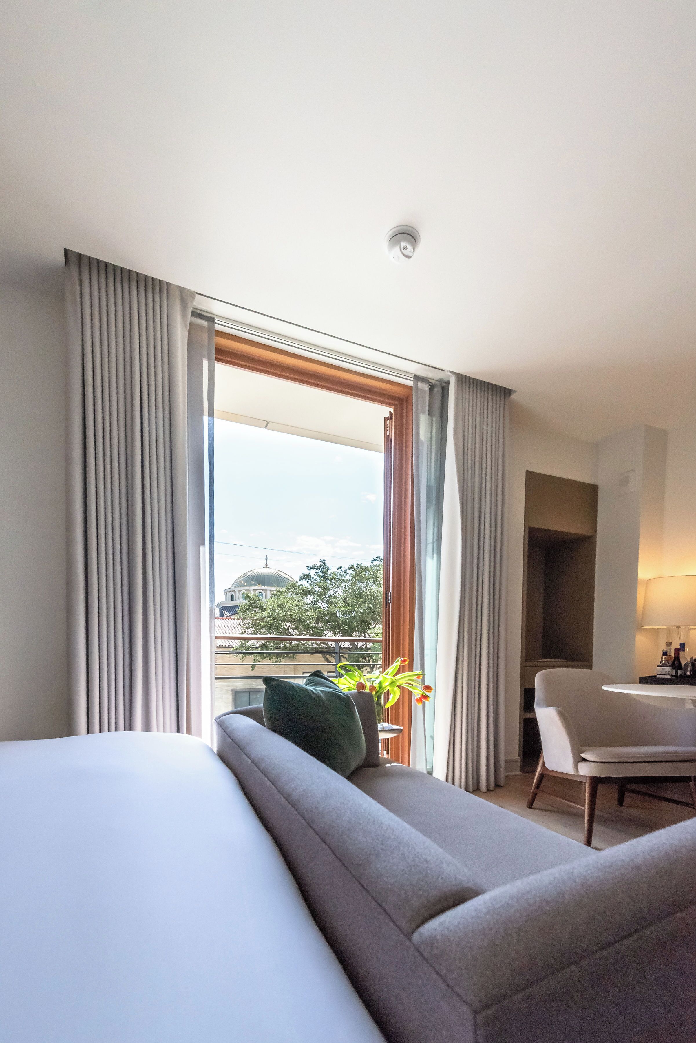 Een moderne hotelkamer met een groot bed, een zithoek, een eethoek en uitzicht op een gebouw met een koepel.