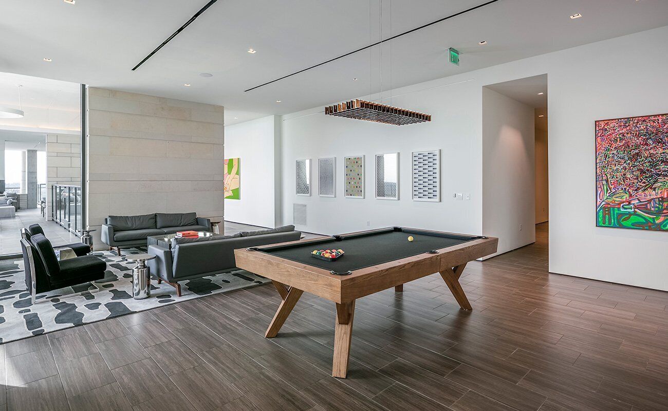 A modern indoor pool area with a pool table, seating, and artwork on the walls.
