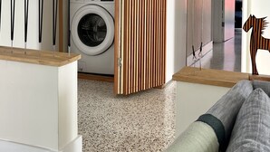 A modern laundry room with stacked washers and dryers, a wooden partition, and a mirror reflecting the room. - Cozy entire house in excellent location , close Brickell , Coconut Grove (Miami)