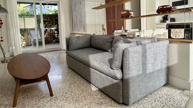 A modern living room with a grey sofa, a round wooden table, and a kitchen area visible through a glass door. - Cozy entire house in excellent location , close Brickell , Coconut Grove (Miami)