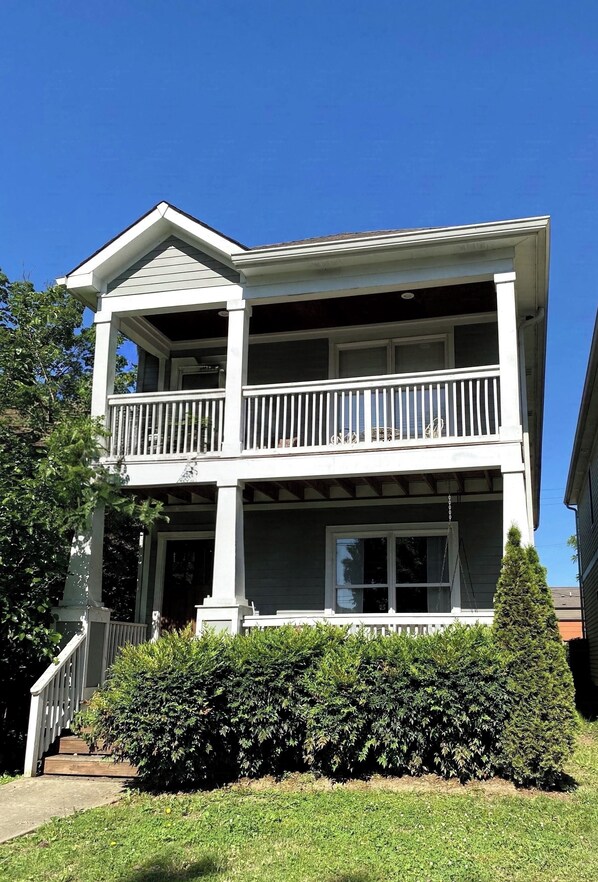 A two-story house with a balcony, a front porch, and a well-maintained hedge. - Licensed, 5 Min To Downtown 4BR, 3.5BA with 2 Master Suites (Nashville)